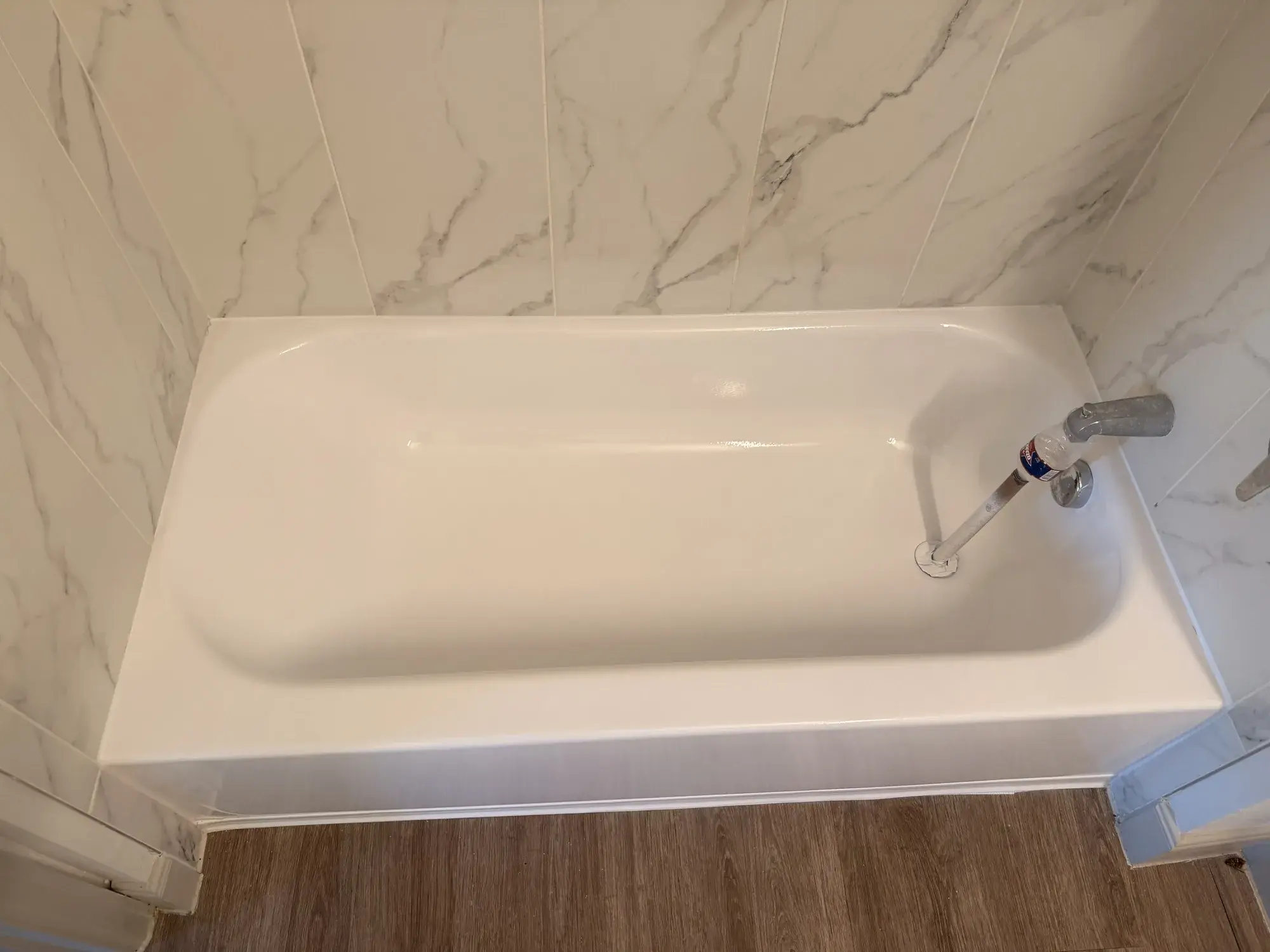 Refinished white bathtub with a marble-look tile surround