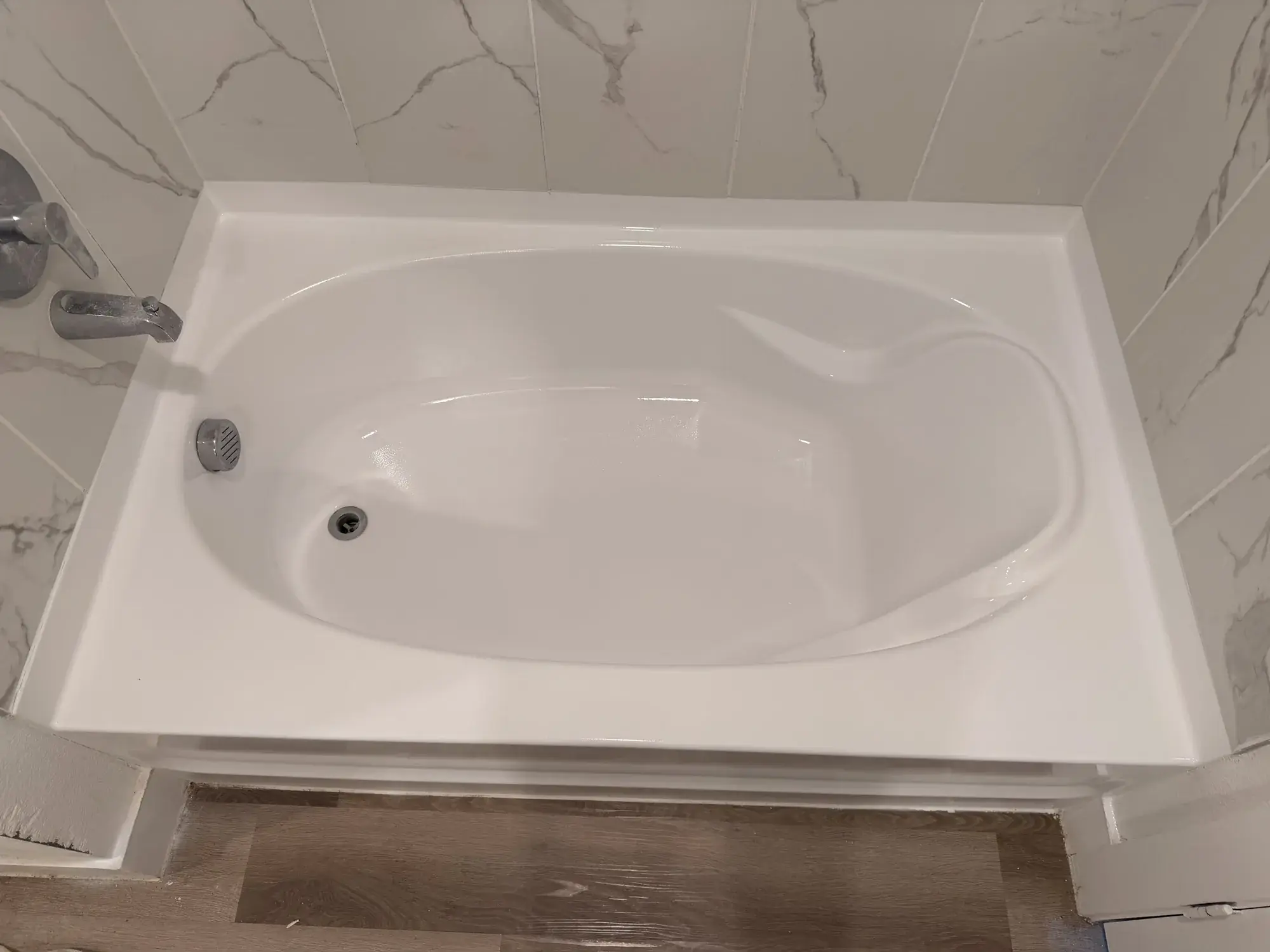 Refinished oval bathtub against marble tile